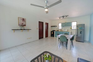 A spacious kitchen with a dining area, a ceiling fan, and a refrigerator. - Central Sosúa Studio: Beaches, Dining & More (Sosúa)