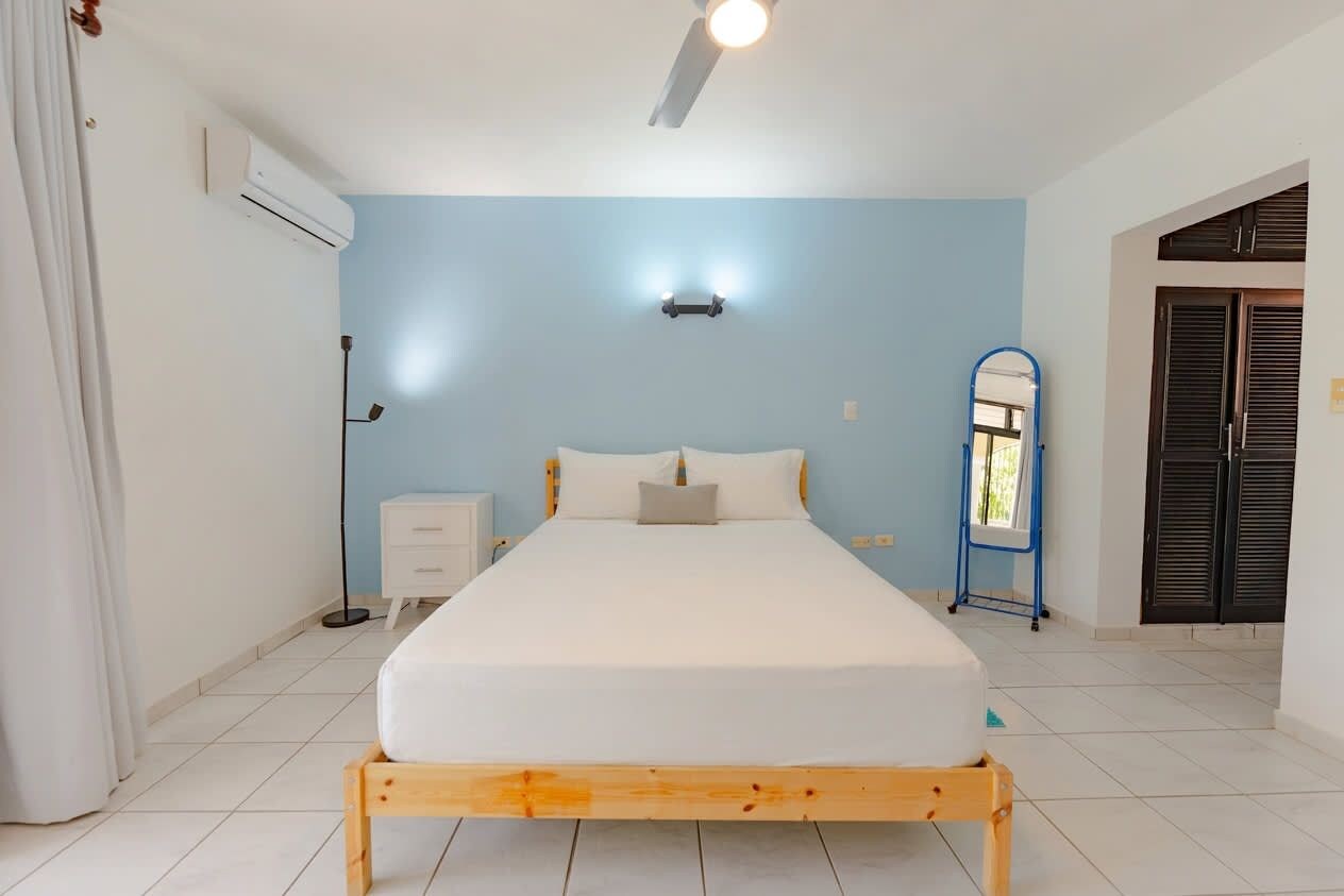 Une chambre à coucher comprenant un lit, une table de chevet et un appareil de climatisation.