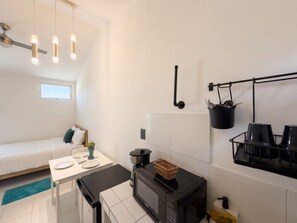 Eine kleine Küche mit Mikrowelle, einem Tisch und einer Küchenutensilienstange.