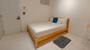 A bedroom with a wooden bed, a white door, a small rug, and a chair. - Studio in the center of Sosua (Sosúa)