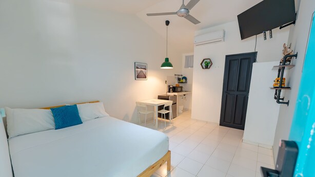 A bedroom with a bed, a desk, and a kitchenette. - Studio in the center of Sosua (Sosúa)