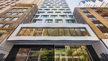 A modern building with a glass facade, a prominent entrance labeled 'The Central 5th Hilton Club,' and a view of the surrounding urban environment.