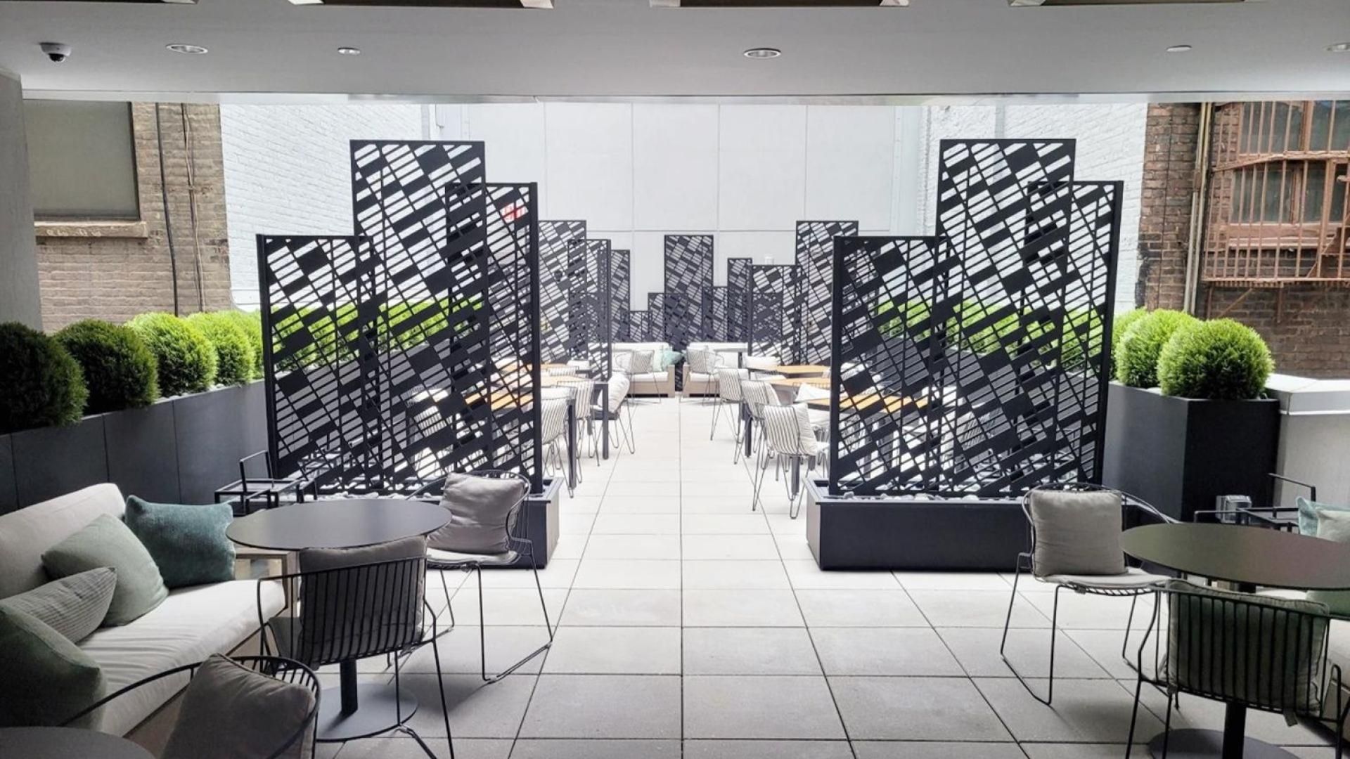 A modern lounge area with sofas, tables, and chairs, separated by black and white patterned partitions.