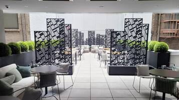 A modern lounge area with sofas, tables, and chairs, separated by black and white patterned partitions.