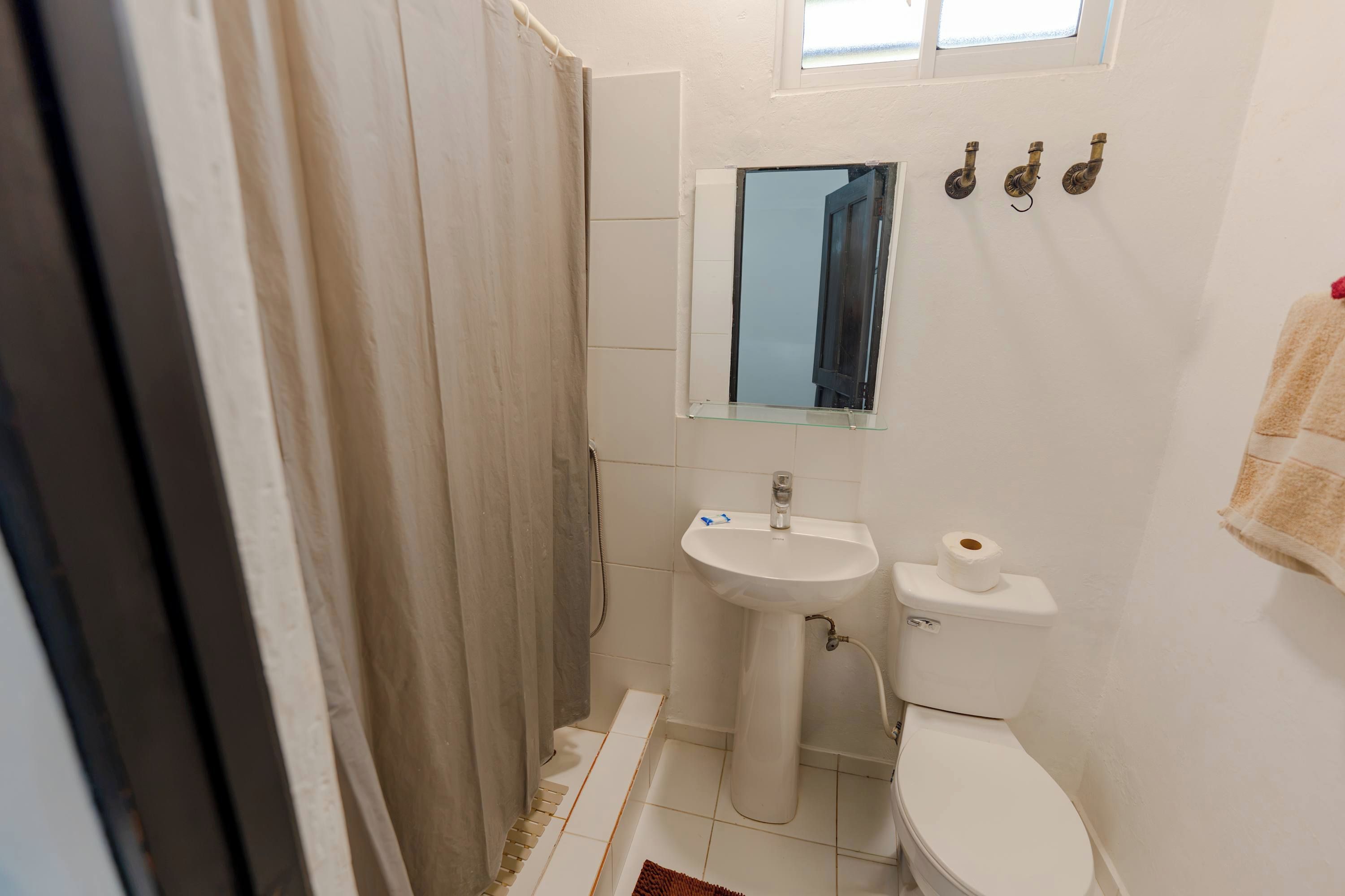 Une petite salle de bain compacte, équipée d’une douche, d’un lavabo et de toilettes.