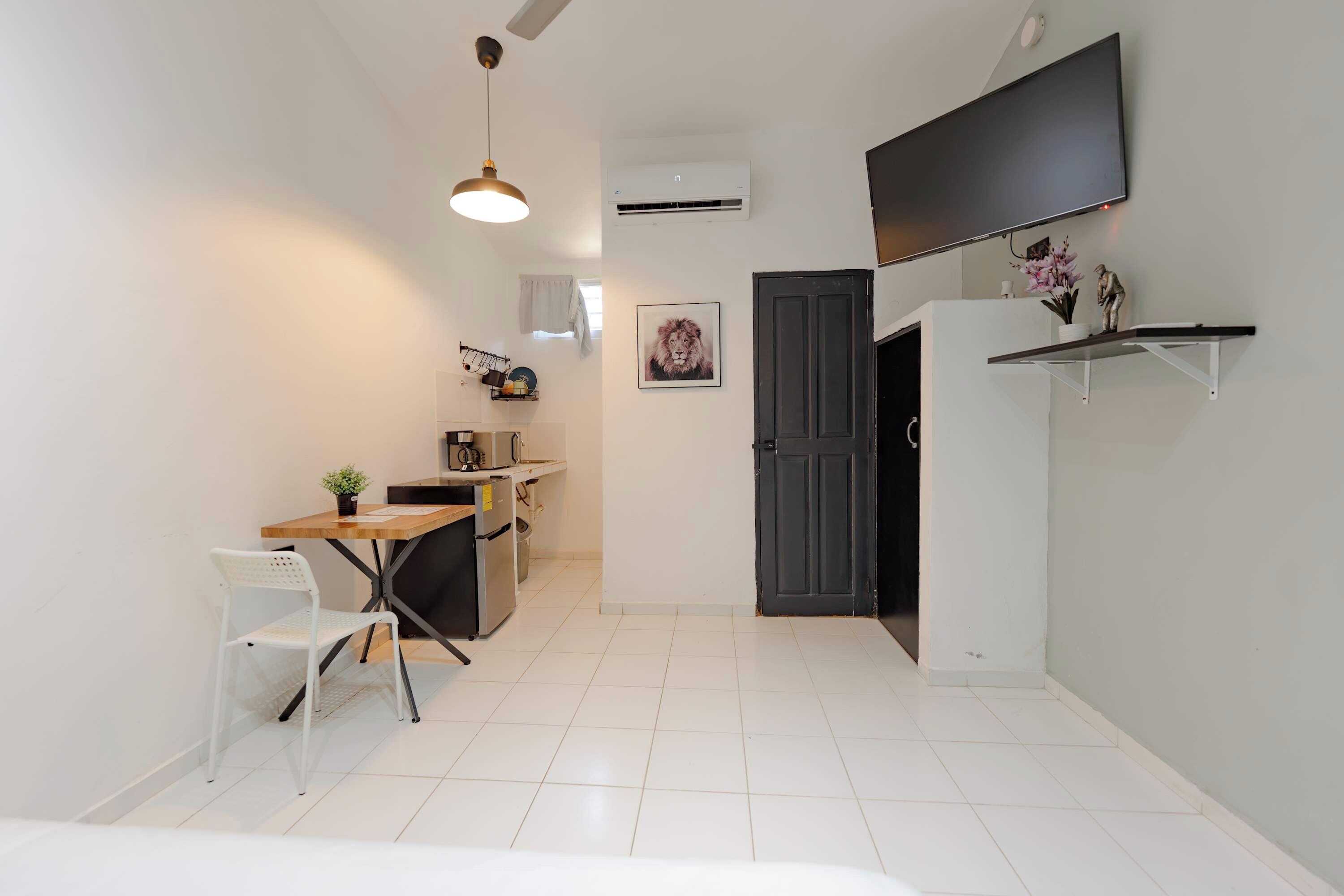 A compact kitchen with a dining area, a black door, and a mounted TV.