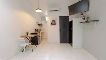 A compact kitchen with a dining area, a black door, and a mounted TV.