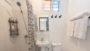 Un bany amb dutxa, rentamig, vàter i una barra per a tovalloles.
