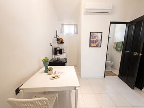 Cocina compacta con una mesa blanca, una cafetera y una pequeña planta en maceta.