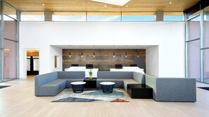 A modern lobby with a sectional sofa, two black tables, and a patterned wall.