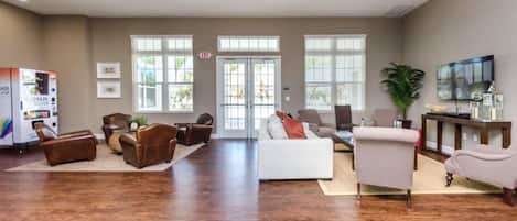 Un salón amplio con un sofá blanco, sillones de cuero, una mesa de centro y un televisor.