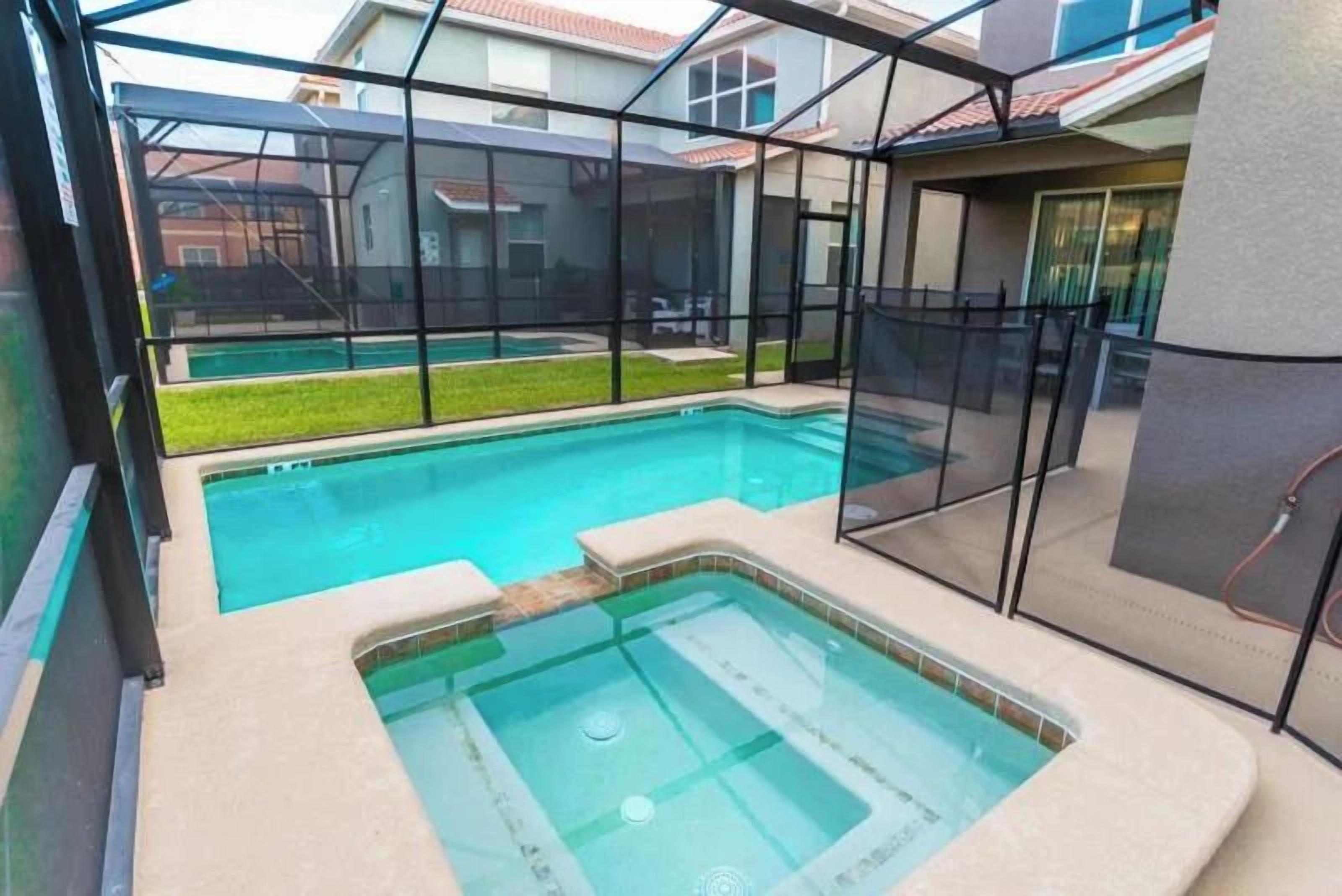 A swimming pool with a hot tub and a covered area with a view of a house.