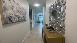 Ein Flur mit einem großen Blumenbild, einem dekorativen Spiegel und einem Holztischchen.