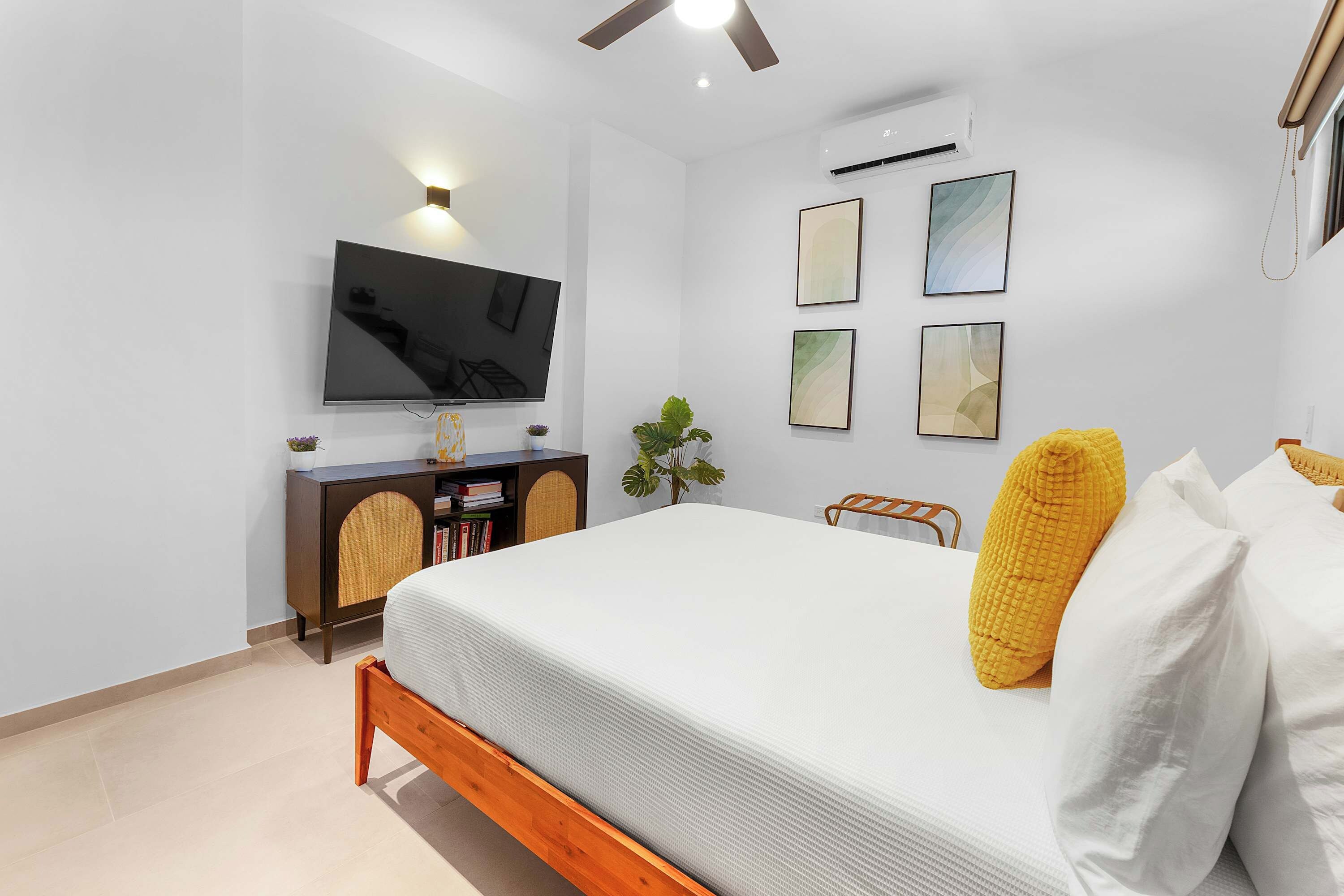 Un dormitorio moderno con una cama, un televisor montado en la pared y un ventilador de techo.