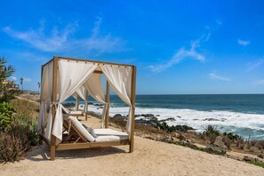 A beach cabana with a single reclining chair and a canopy, overlooking the ocean. - Oceanfront Cove Condo | Ocean-View Terrace & Pool (El Pescadero)