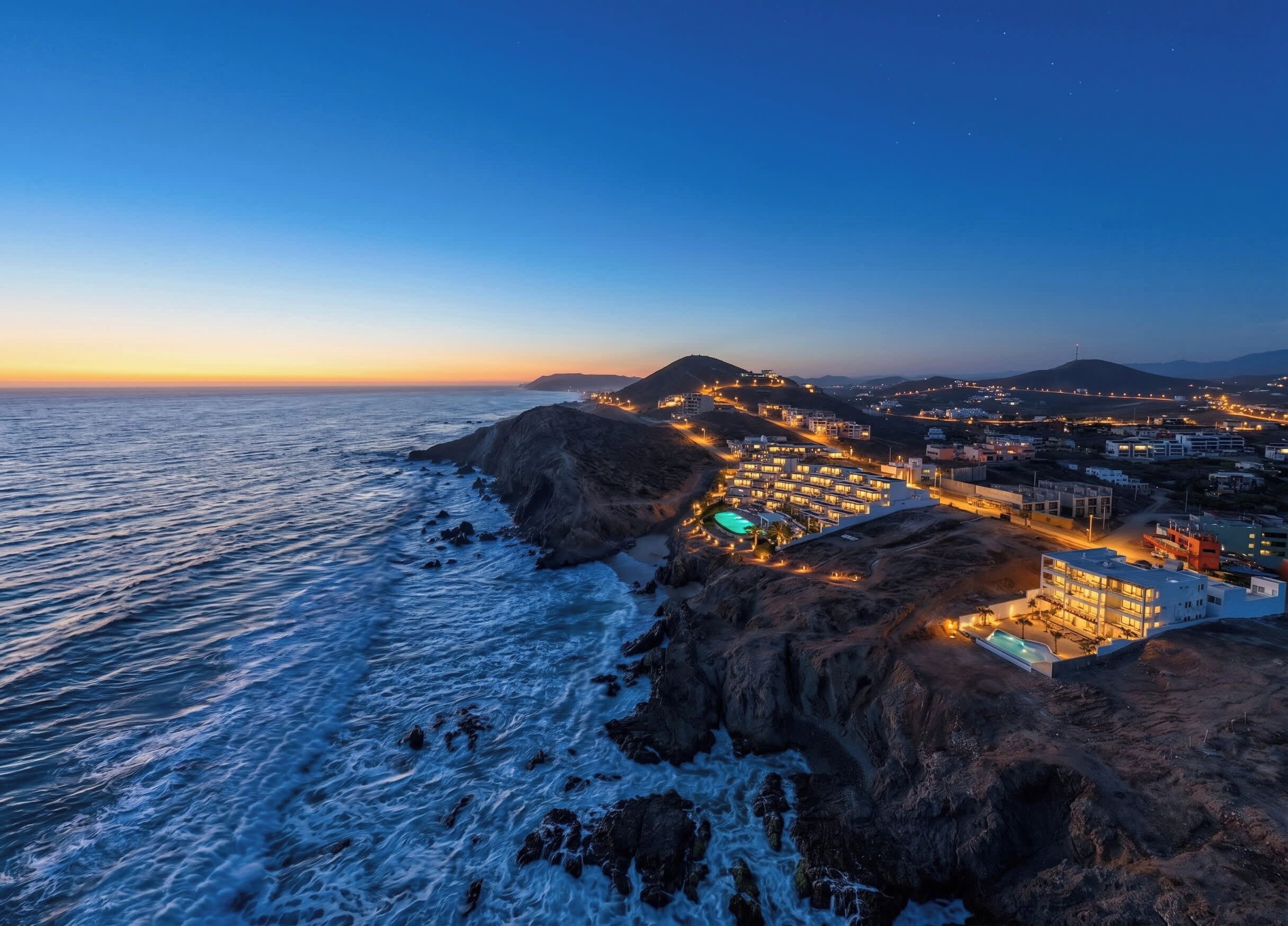 A coastal hotel with a pool, overlooking the sea and a cityscape.