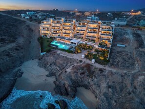Un complesso alberghiero moderno con diversi edifici, una piscina e un paesaggio roccioso.