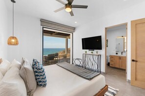 Ein Schlafzimmer mit Bett, Kissen, Fernseher und Meerblick.