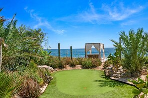 Un jardin bien entretenu, offrant une vue dégagée sur l’océan, agrémenté d’une pergola et d’une grande variété de plantes.
