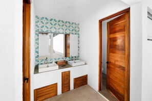 Een badkamer met twee wastafels, een spiegel en een houten deur.