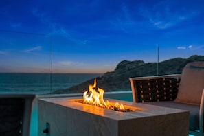 A fire feature with a view of the ocean and a mountainous landscape. - Oceanfront Cove Condo | Ocean-View Terrace & Pool (El Pescadero)