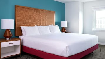 A hotel room with a large bed, two bedside tables, a nightstand, and a window.