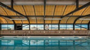 A swimming pool with a view of the ocean through large windows.
