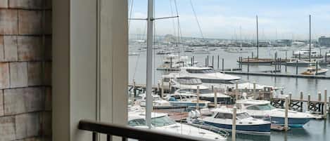 A marina with multiple boats docked, viewed from a balcony with a railing.