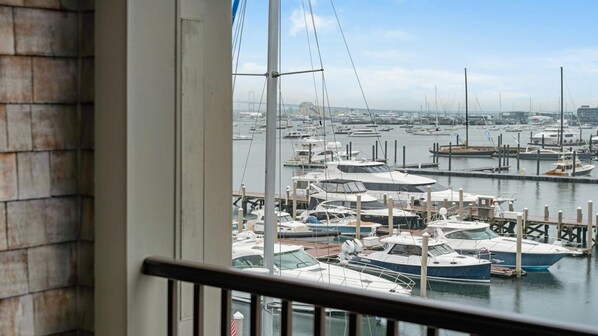 A marina with multiple boats docked, viewed from a balcony with a railing.