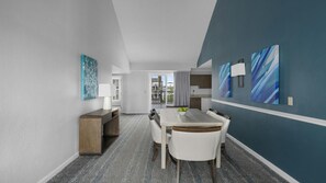 A modern dining area with a table and chairs, a small side table with a lamp, and abstract wall art.