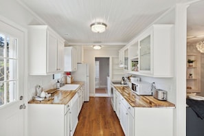 A kitchen with white cabinetry, wooden countertops, and a central island. - Quaint Cottage-Great Location with Hot Tub! (Mount Pleasant)