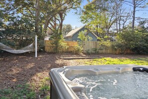 A hot tub in a backyard with a hammock, wooden fence, and trees. - Quaint Cottage-Great Location with Hot Tub! (Mount Pleasant)