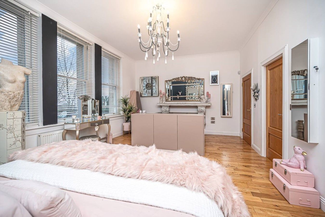 Ett sovrum med en stor säng, en byrå, en sminkbord och en kristallkrona.