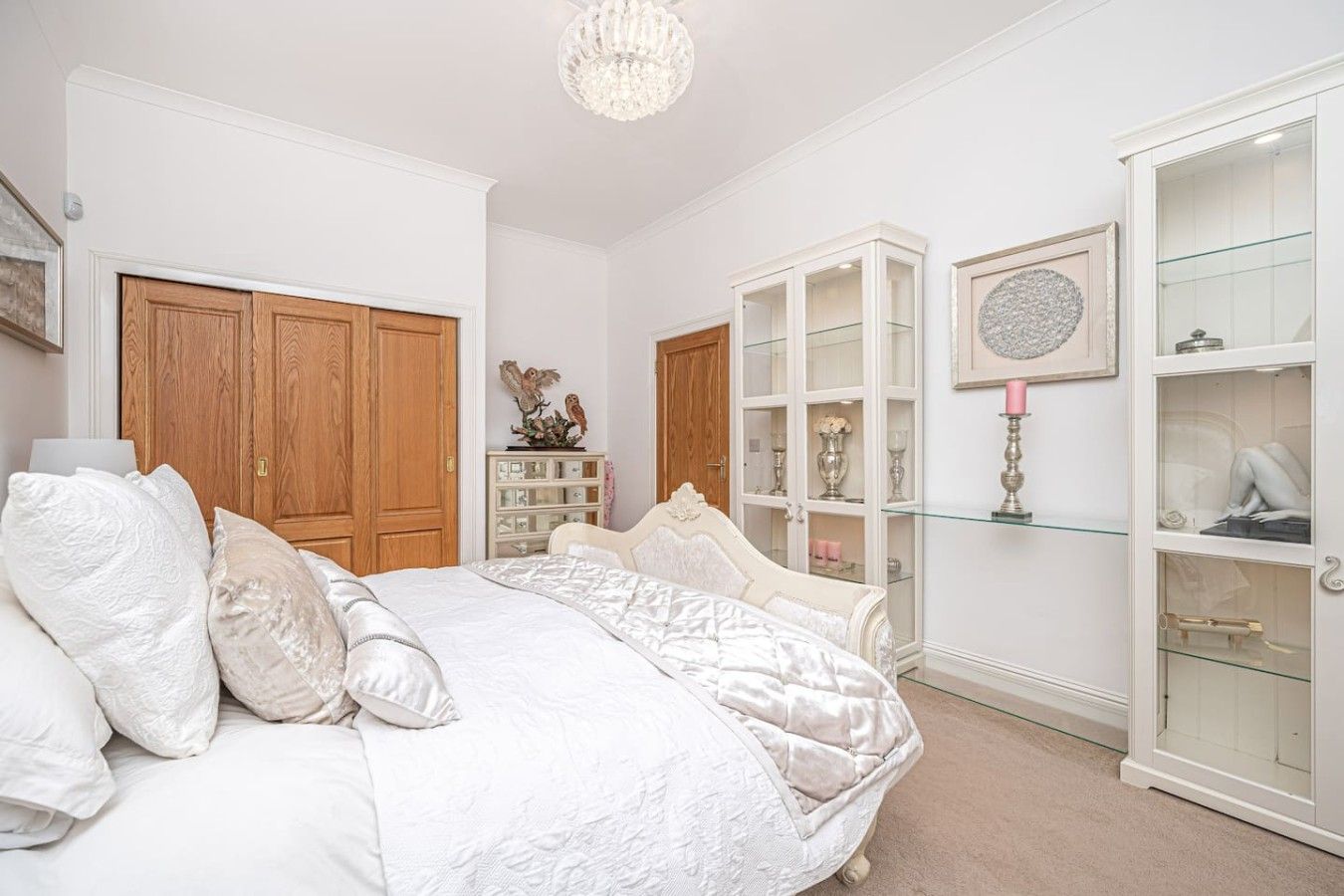 A bedroom with a large bed, a wardrobe, and a glass cabinet.