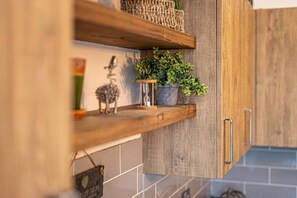 Una cocina con estantes de madera, una planta en maceta y un objeto decorativo.