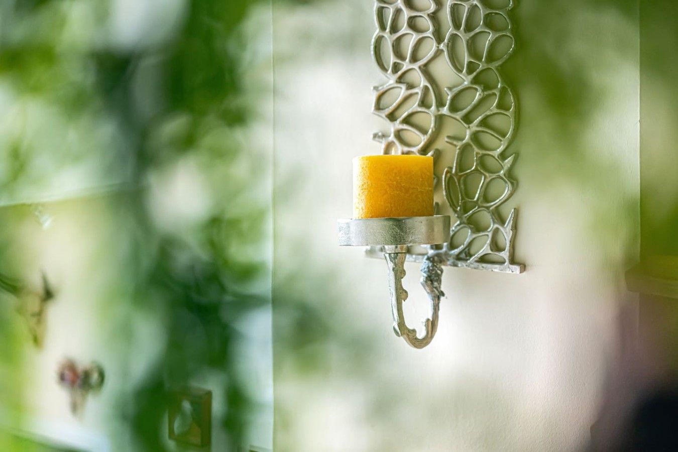 Un objeto amarillo que cuelga de un accesorio metálico con diseño de hoja.