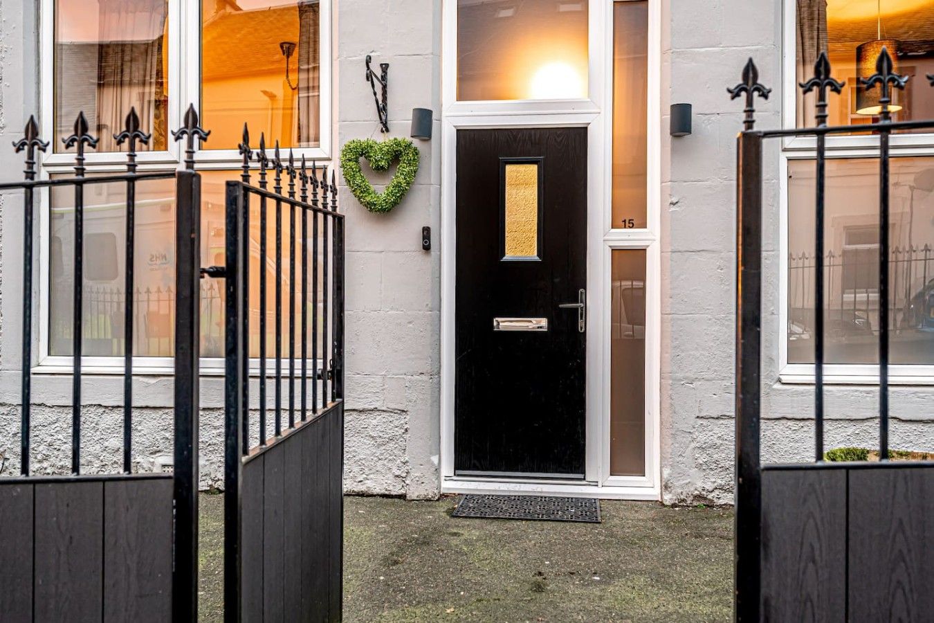 A black door with a small window above it, a heart-shaped decoration on the wall, and a number '15' on the door.
