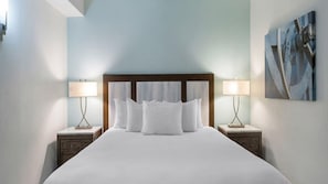 A hotel room with a large bed, two bedside tables with lamps, a wooden headboard, and a painting on the wall. - Newport RI Waterfront 1BR Suite w/ Jetted Tub - WorldMark Inn on Long Wharf (Newport)