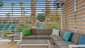 Un área de estar exterior moderna con un sofá modular, una mesita redonda y un ventilador.