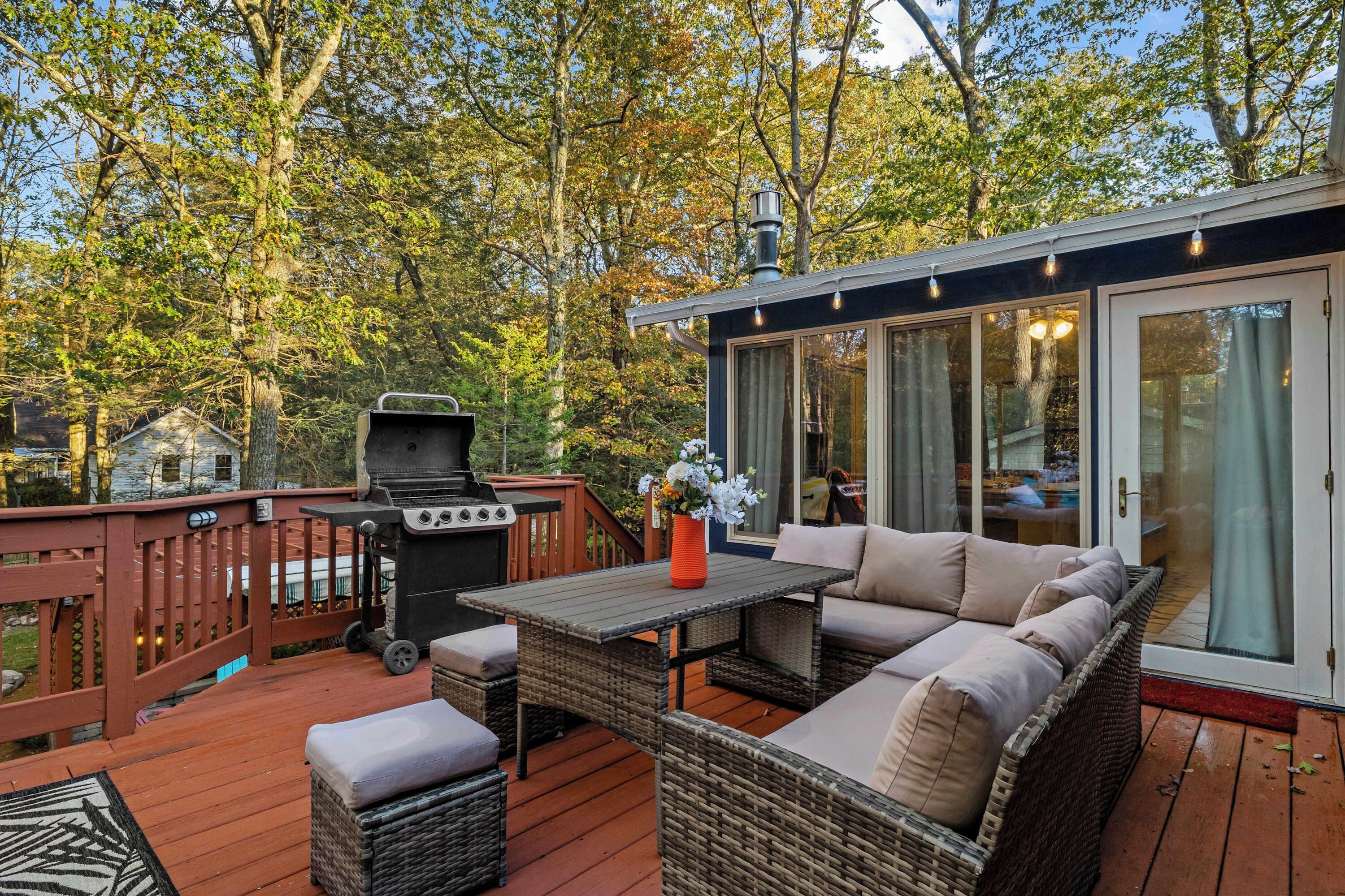 An outdoor deck with a grill, wicker furniture, and a glass-enclosed patio area.