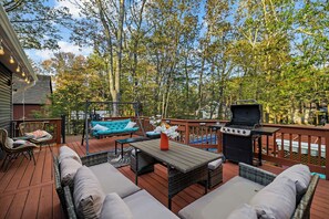 Eine Terrasse mit Gartenmöbeln, einem Grill und einer hängenden Leuchte.