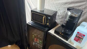 Una kitchenette equipada con microondas, cafetera y refrigerador.