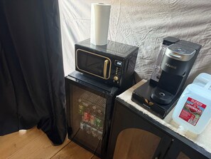 A kitchenette with a microwave, coffee maker, and refrigerator.