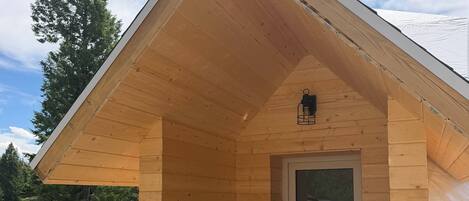 A wooden cabin with a sloped roof, a glass door, and a wooden deck.