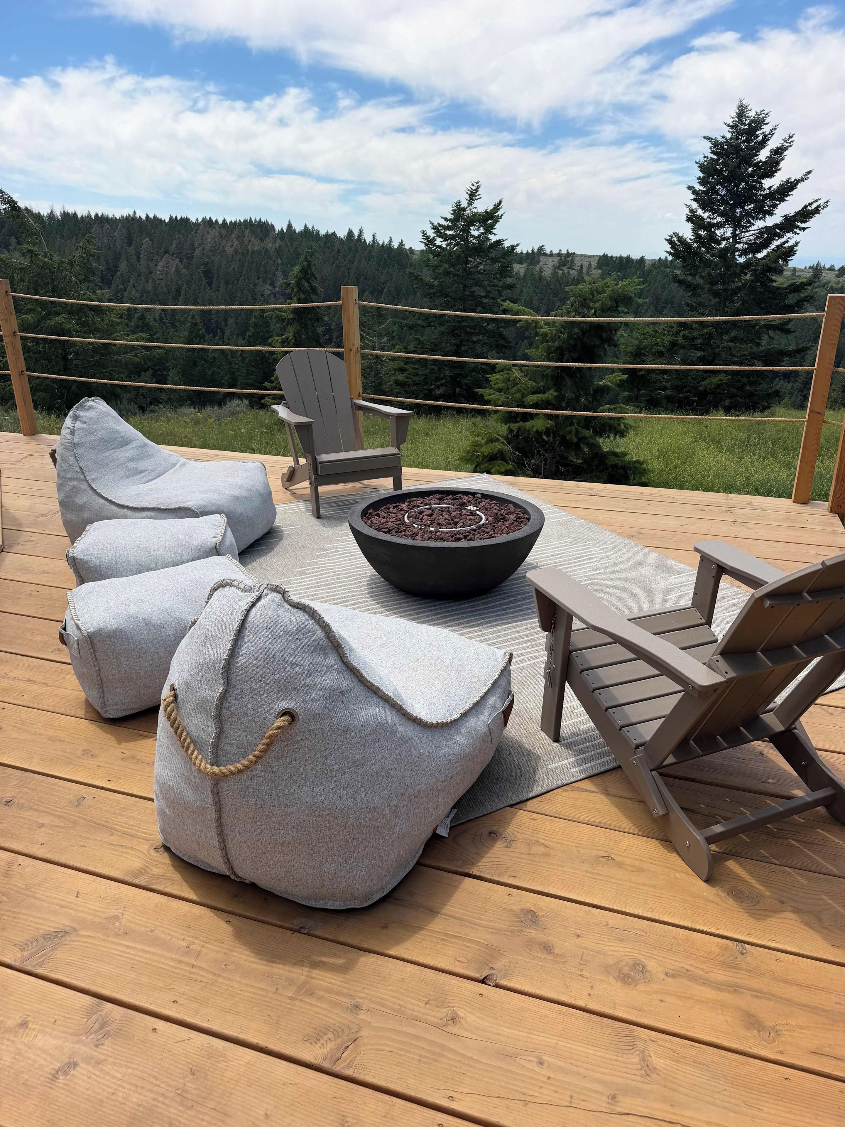 A deck with a fire pit, two Adirondack chairs, and two bean bags.