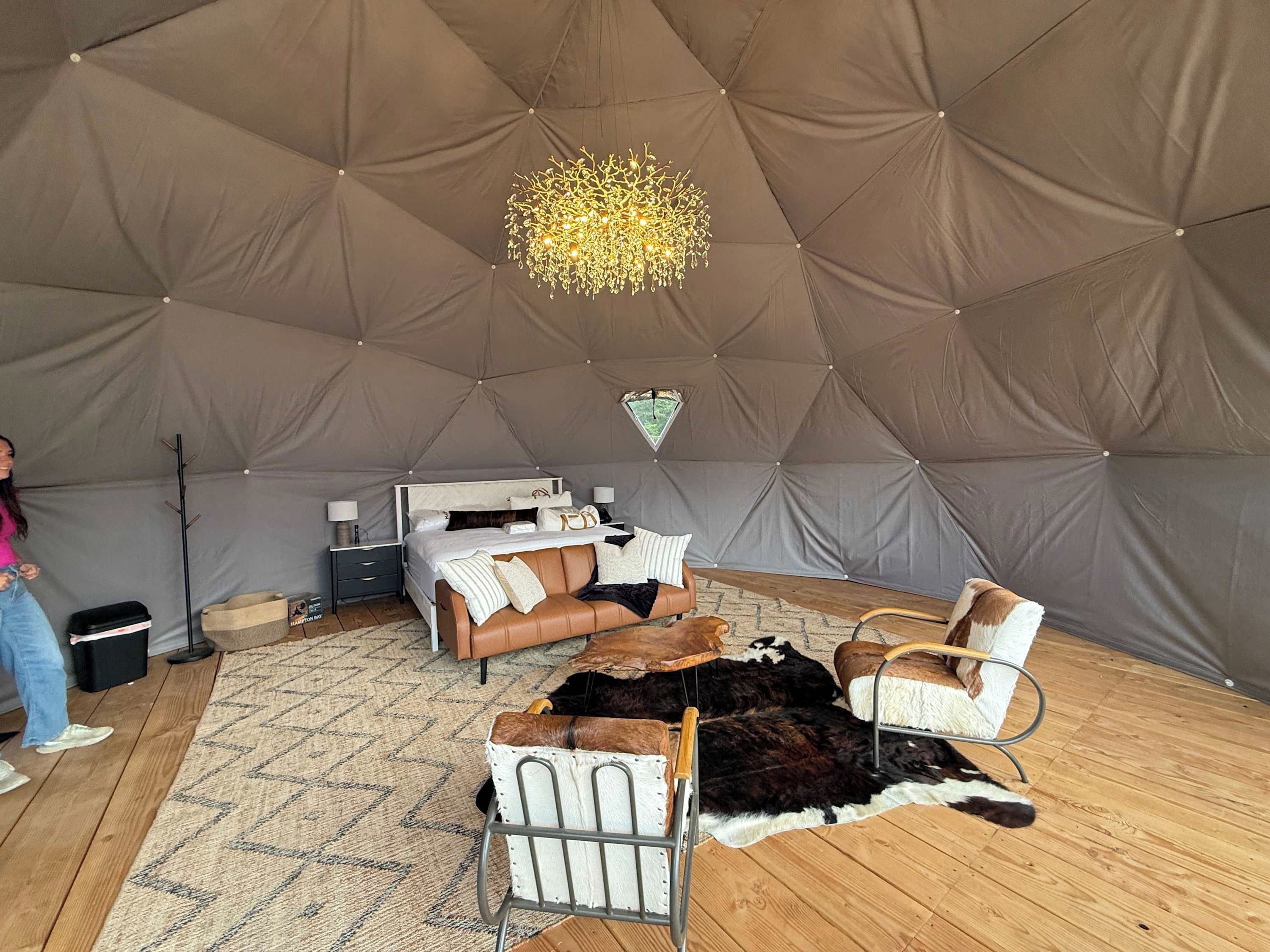 A tented room with a bed, a seating area with chairs, a rug, and a fur rug on the floor.