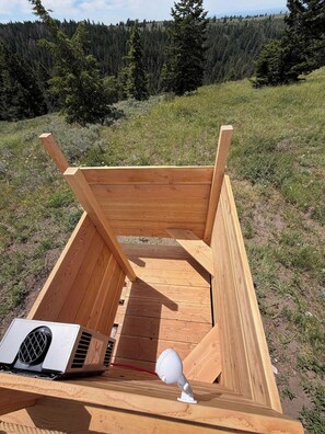 A wooden structure with a bench, a ventilation unit, and a white object on top.