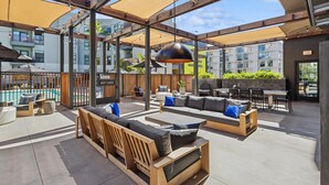 An outdoor seating area with wooden furniture and a pool in the background. - Botanical Escape' Large Balcony Heart of Hollywood (Los Angeles)