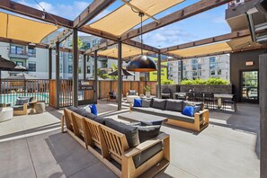 Un área de estar al aire libre con muebles de madera y una piscina al fondo.