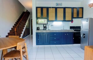 A kitchen with dark blue cabinets, a stainless steel refrigerator, and a wooden dining table with chairs. - Condominio a solo unos pasos de la hermosa playa con gran piscina!! (Las Terrenas)